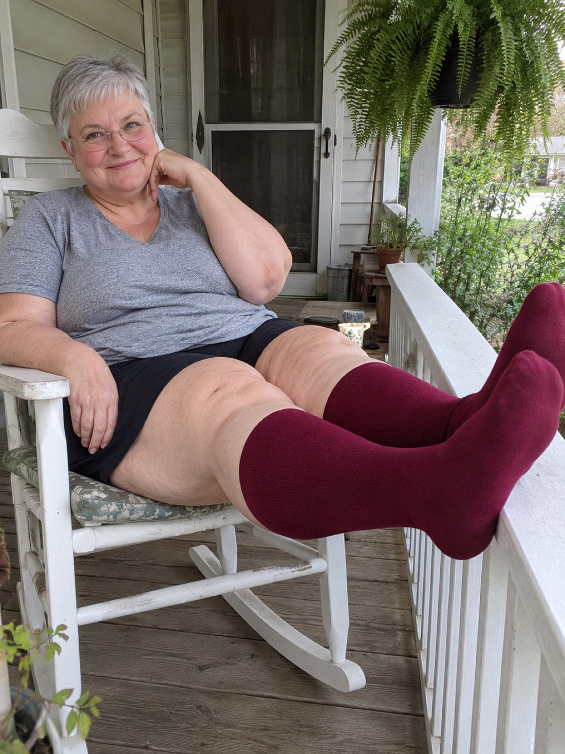 Woman relaxing on her porch with her feet up in Comfyso Bamboo compression socks in Rich Burgundy.