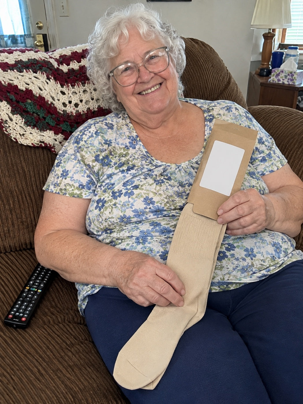 Woman in her recliner at home holding a new pair of Comfyso Premium Bamboo Wide Compression Socks in Soft Beige.